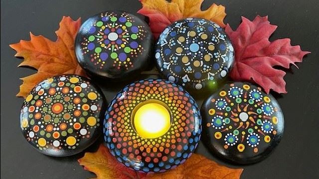 Colorful round rocks, one with the center cut out for a candle